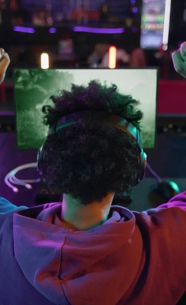 Speler viert een overwinning in een moderne gamingruimte met neonverlichting en game-over-schermen